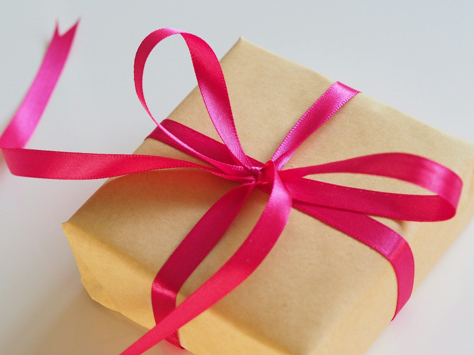 A kraft-paper gift tied with a pink satin ribbon