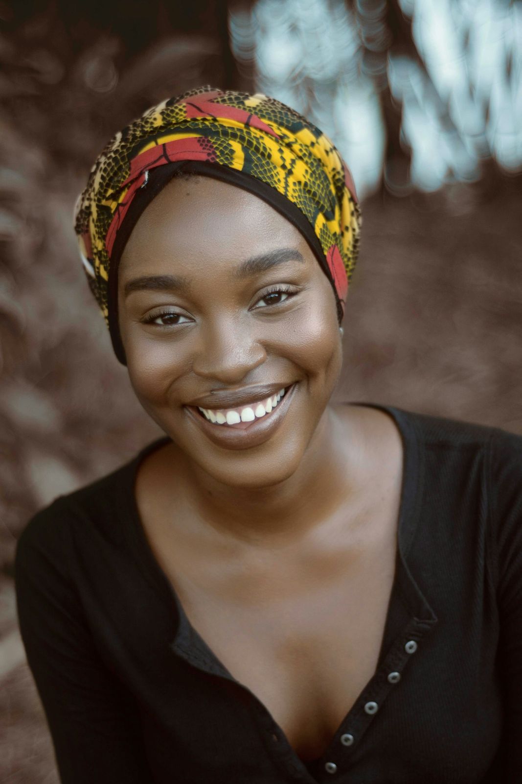 A smiling woman in a colourful headwrap